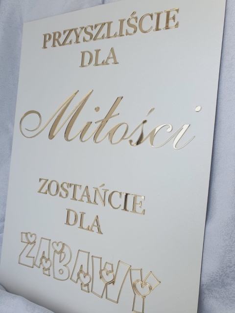 „Zbliżenie na złoty napis z akrylu na białej tablicy powitalnej.” „Zbliżenie na złoty napis z akrylu na białej tablicy powitalnej.”